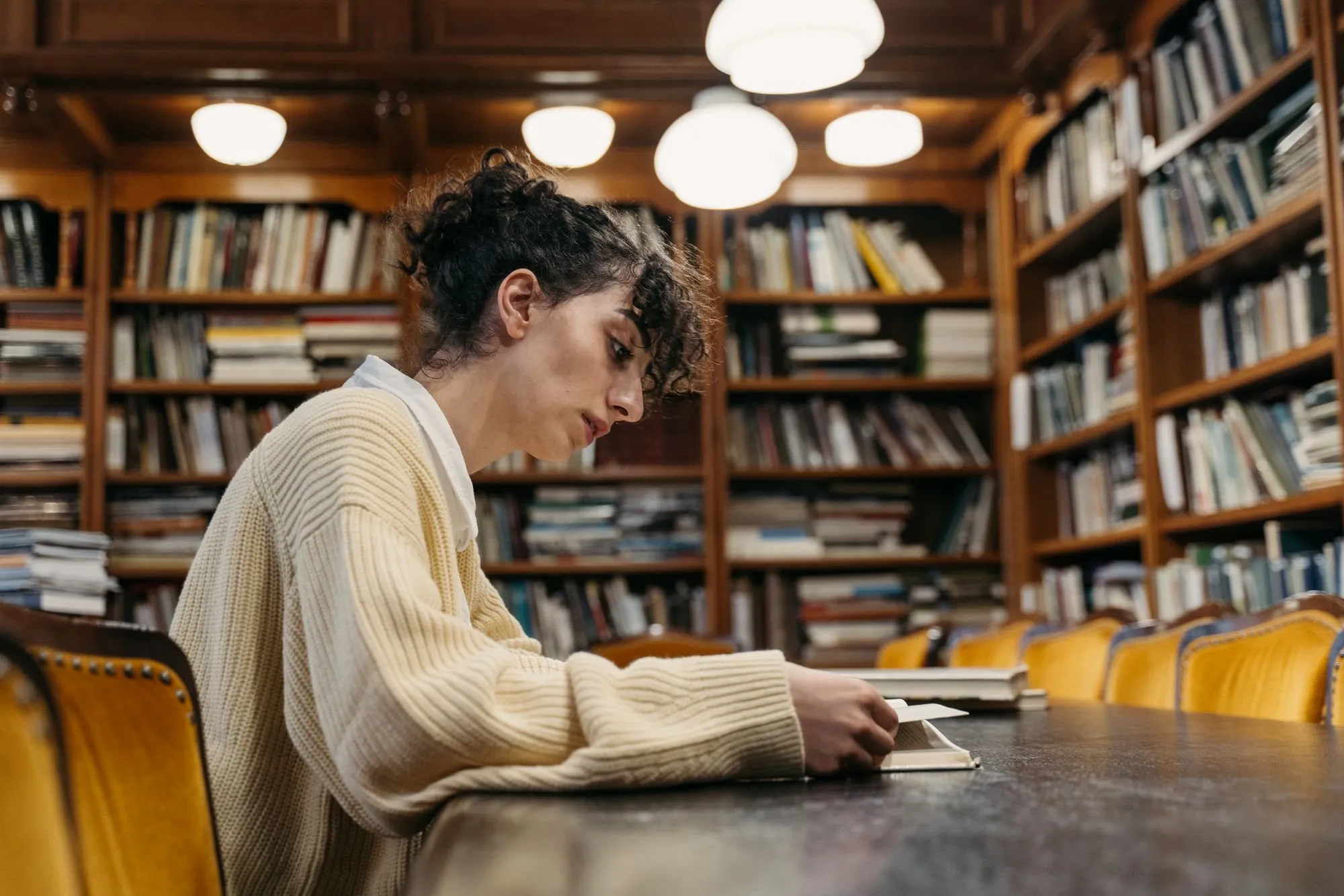 Eine Studentin liest an einem Tisch in einer Bibliothek