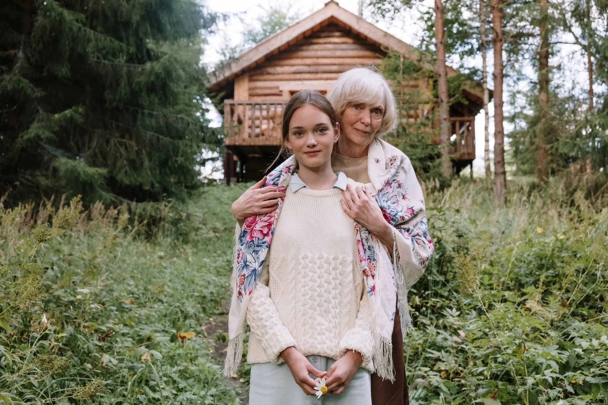 Eine Großmutter und ihre Enkelin stehen Arm in Arm in einem Garten