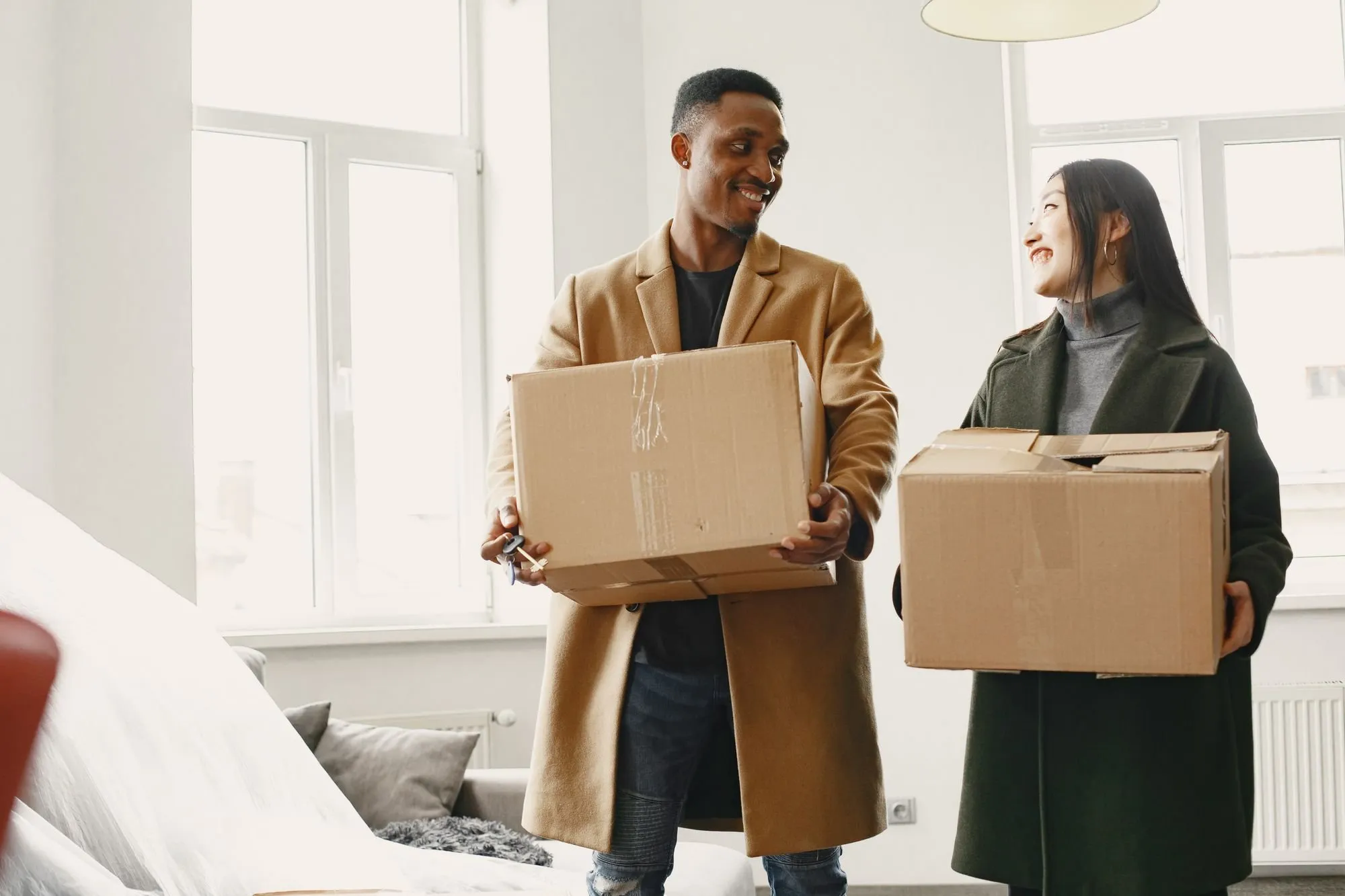 Ein Paar trägt Umzugskartons in eine helle neue Wohnung